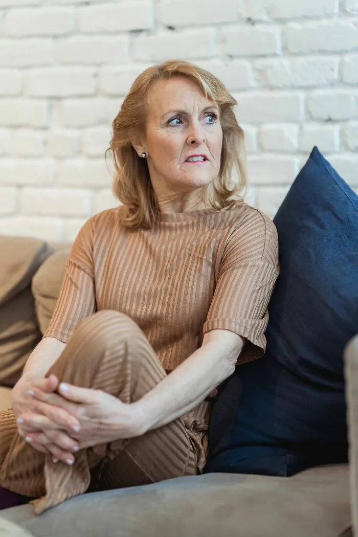 Older woman looking worried on couch, representing painful family cut off reasons