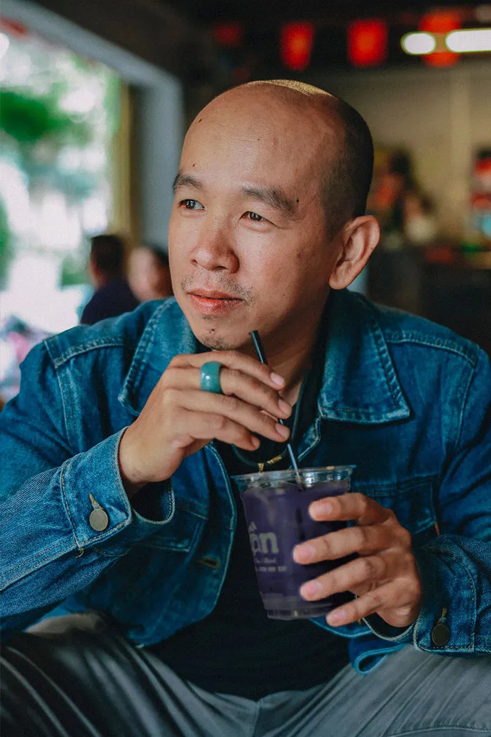 A patient in a denim jacket drinking a purple beverage through a straw, relating to patient wellbeing.