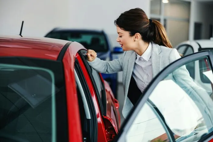 A woman looking at a new red car, highlighting details on why men lose interest in a woman