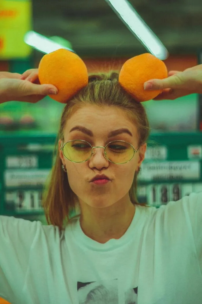 A goofy woman holding oranges like ears, a playful act that can make men lose interest