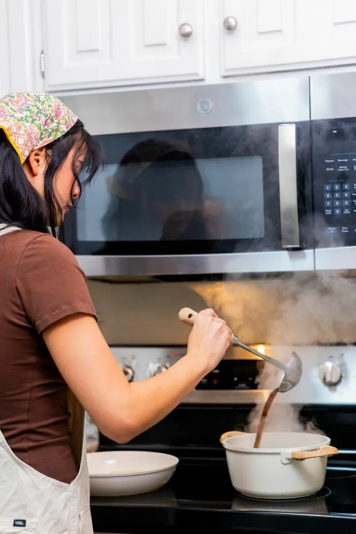 A woman cooking at the stove, reflecting on small things that cause men lose interest in a woman instantly