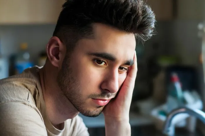 A sad, reflective man in a kitchen, thinking about why men lose interest in a woman