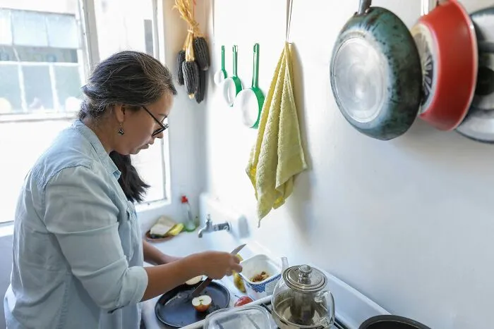 A woman slicing apples in a kitchen, showing how entitled parents might demand homemade snacks