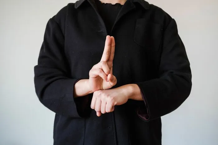 A person in a black jacket demonstrating sign language, indicating communication barriers with entitled parents.