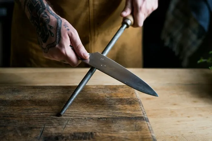 A person sharpening a chef knife on a steel rod during a divorce split dispute.