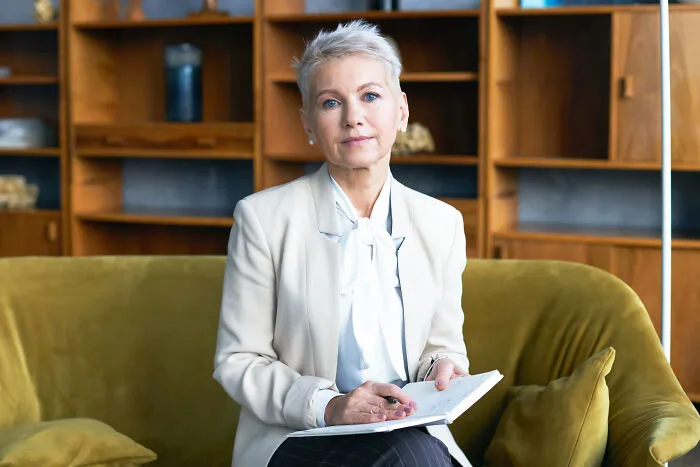 A professional woman sitting on a couch with a notebook, reflecting on subtle sexism.