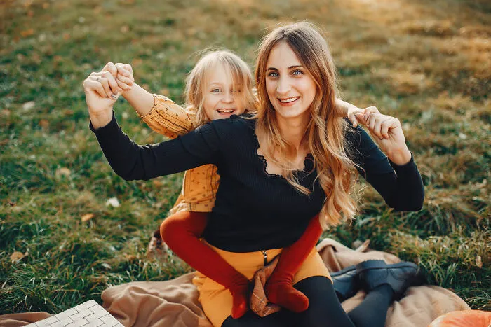 Mother and daughter smiling together outdoors, focusing on happy family life