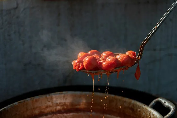 Metal ladle lifting steaming cooked tomatoes, illustrative of unusual diets in strange patients.