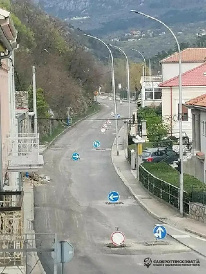 An overhead view of a street cluttered with multiple conflicting blue arrow signs on the road surface.