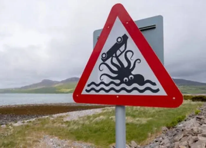 Funny warning sign of a giant kraken attacking a car near the coast, looking like a sign mistake.