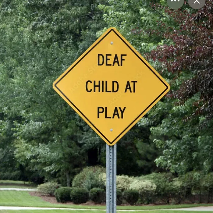 A yellow diamond road sign reading Deaf Child At Play, showing a sign mistake in wording.