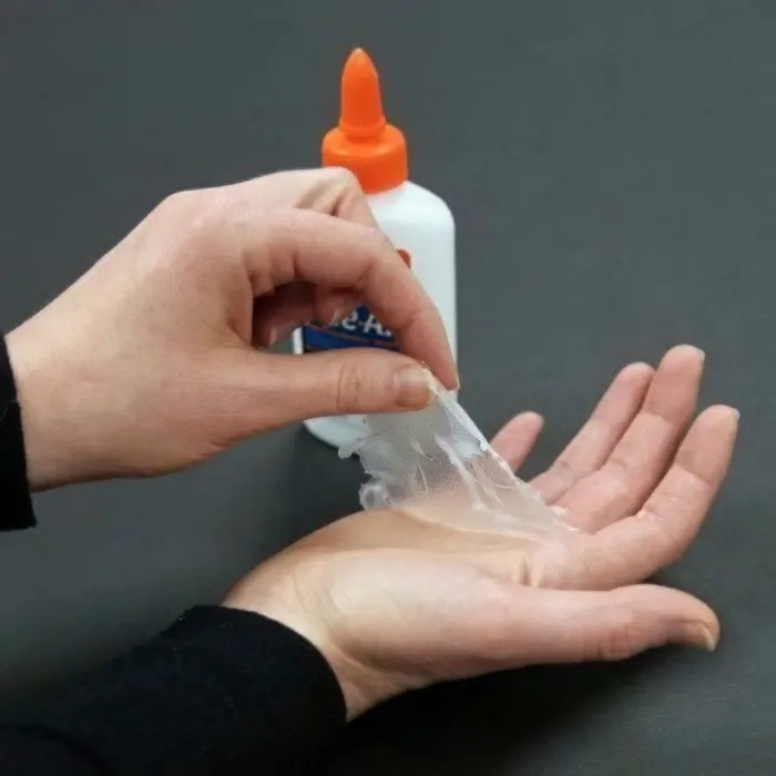 Peeling dried glue skin from hand showing old school liquid glue