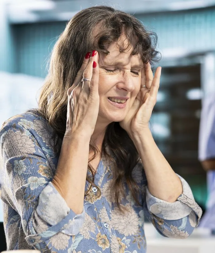 A stressed woman holding her head, showing having money and having class are different