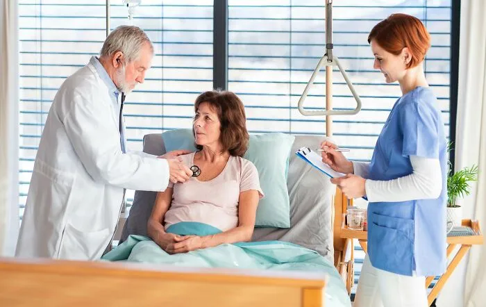 Doctor checking a patient in bed while a nurse takes notes, relating to strange things said under medication.