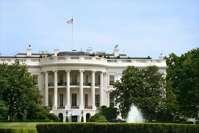 White House exterior with fountain and American flag in bright daylight