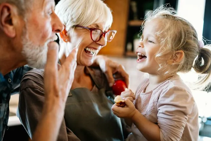 Grandparents laughing and sharing a moment with their young granddaughter