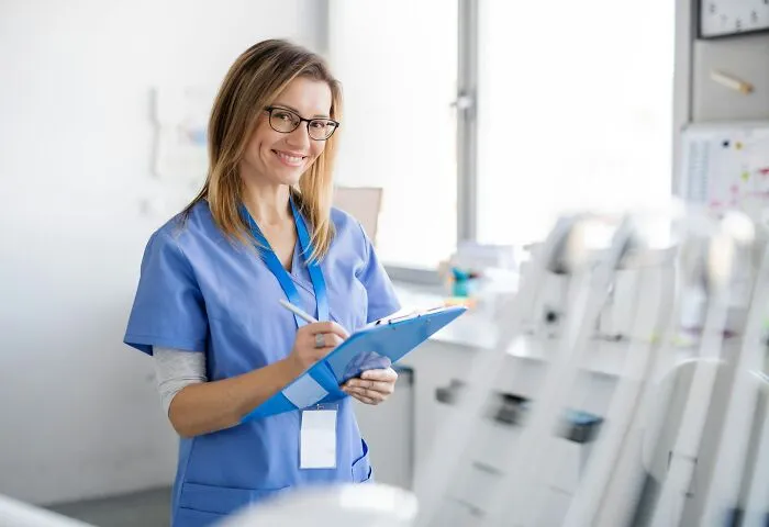 A smiling anesthesiologist taking notes, representing the professionals hearing bizarre things people said under medication.