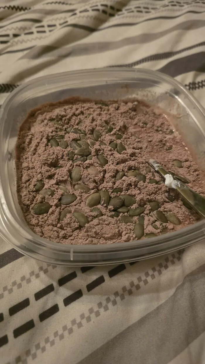 Unusual food combinations with chocolate pudding sprinkled with pumpkin seeds and chocolate powder.