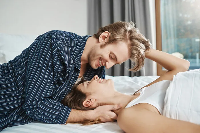 Affectionate young couple smiling in bed, free from marriage regrets