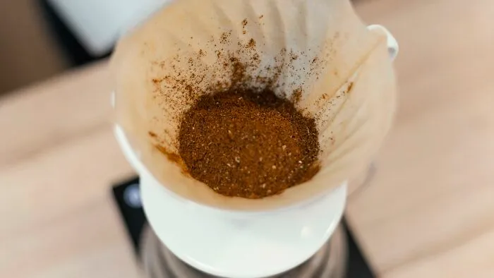 Freshly ground coffee beans in a paper filter, illustrating cheap but effective morning routines