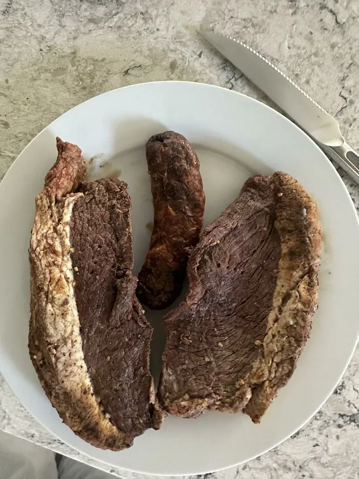 Slices of cooked steak and a sausage on a white plate, representing classic food combinations.