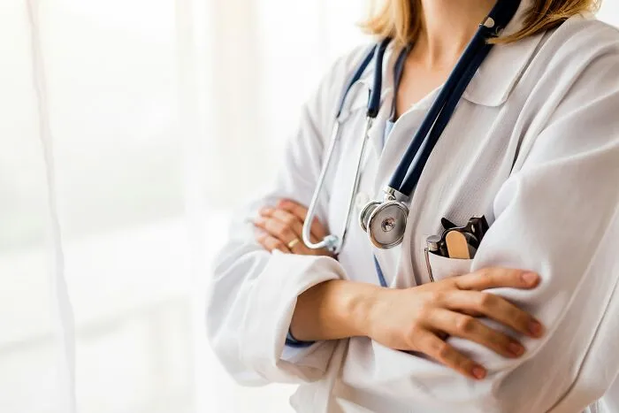 A healthcare worker in a white coat with folded arms, symbolising the current job market.