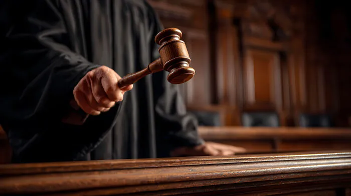 A judge's hand holding a gavel in a courtroom, symbolizing a legal career life path for smart kids.