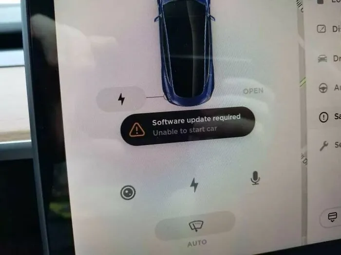 A car screen displaying a software update required warning that prevents starting, a terrible product design