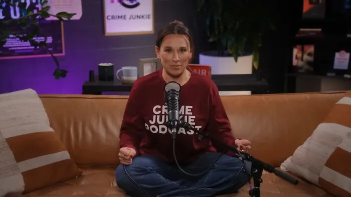 A podcast host in a Crime Junkie shirt, speaking on industry secrets of media businesses