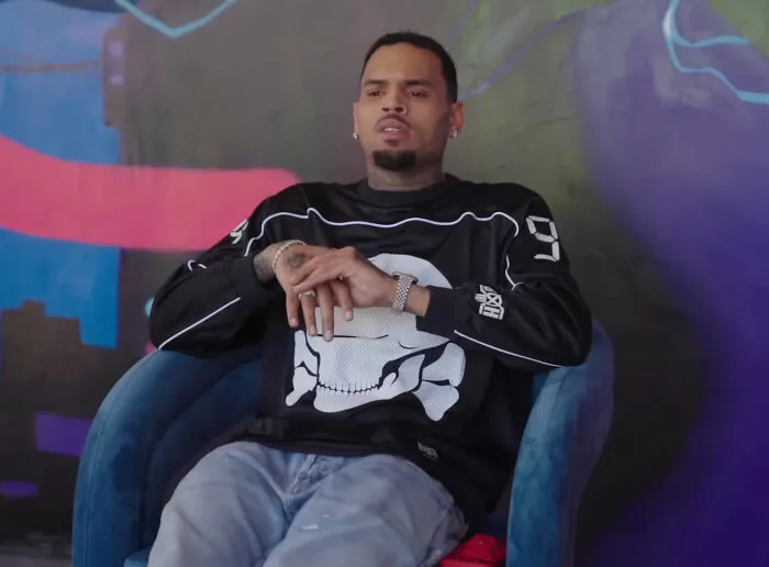 Singer Chris Brown sitting in a chair, representing industry secrets in music businesses