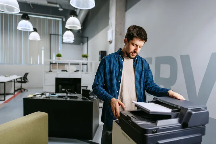 A man working at a copier machine in an office, potentially feeling marriage regrets