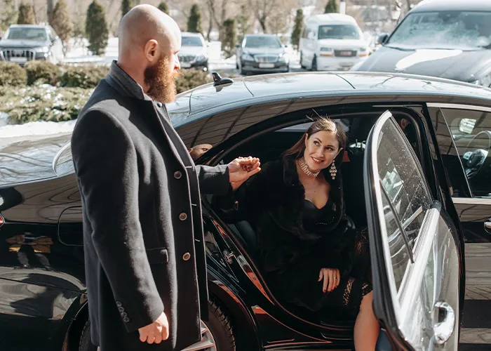 A gentleman opening a car door and offering a hand to a woman, showing classic chivalry in relationships.