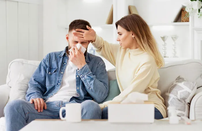 Woman checking forehead of sick man showing care despite toxic relationship traits