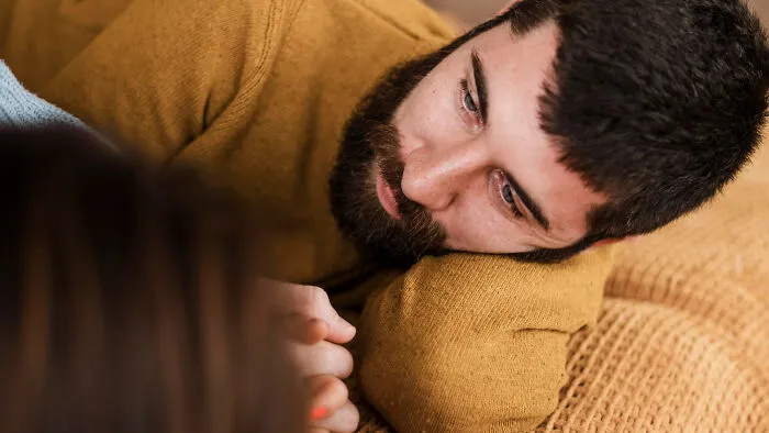 Man lying down looking sad depicting toxic traits in relationships