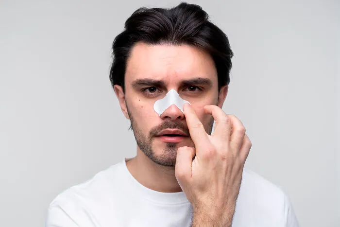 A man applying a pore strip to his nose, representing sweet and funny patient stories of self-care