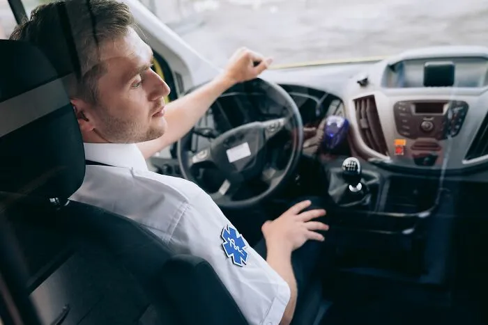 An EMS medical worker driving an ambulance, ready to help with patient stories.