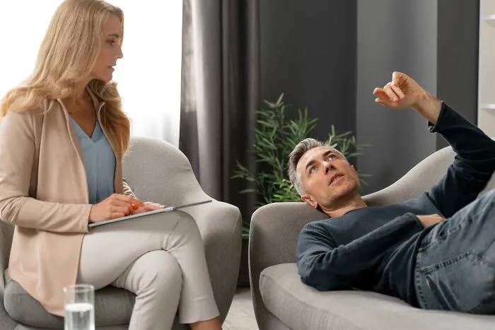 A man lies on a therapist couch, discussing his personal marriage regrets