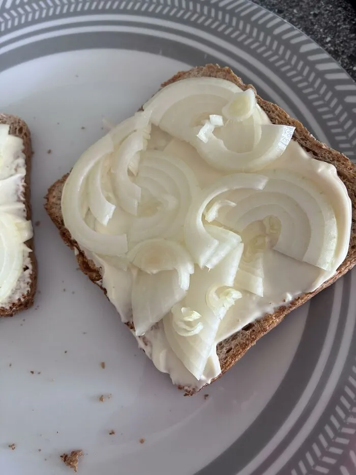Strange food combinations with sliced raw onions on a piece of white-spreaded toast