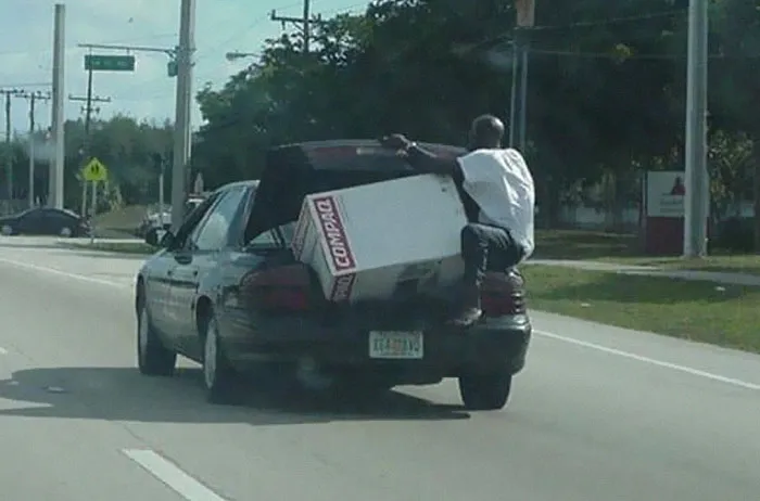 Man hanging on car trunk while transporting large box in moving fails pics