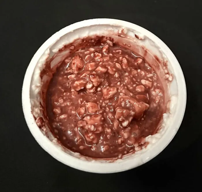 Odd food combinations showing cottage cheese mixed with a dark red jelly in a white plastic container