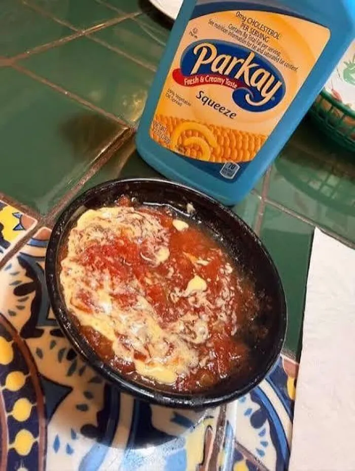 A bowl of red salsa drizzled with squeeze margarine, illustrating strange food combinations.