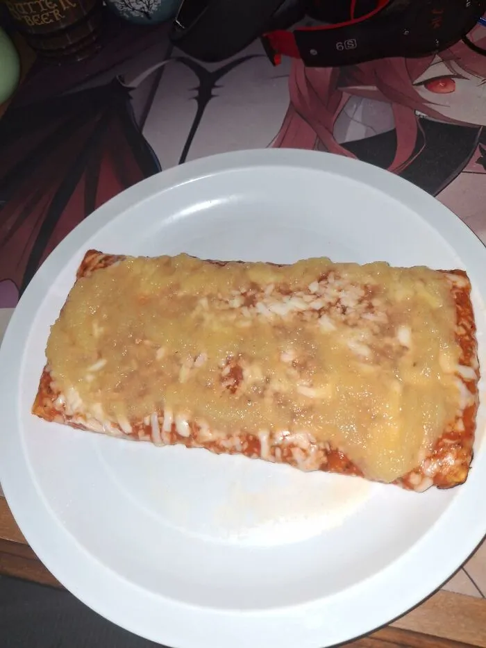 A rectangular pizza slice topped with applesauce, demonstrating weird food combinations.