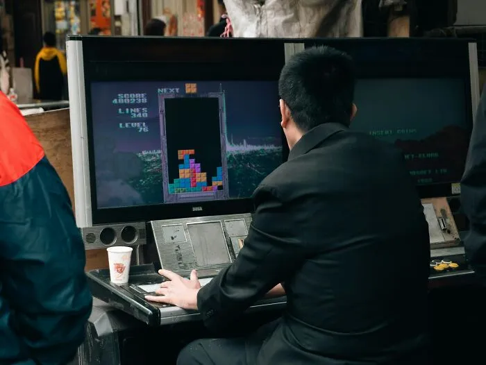 Man playing arcade game Tetris focused on screen in public