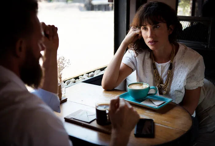Woman listening intently to man during serious coffee shop conversation
