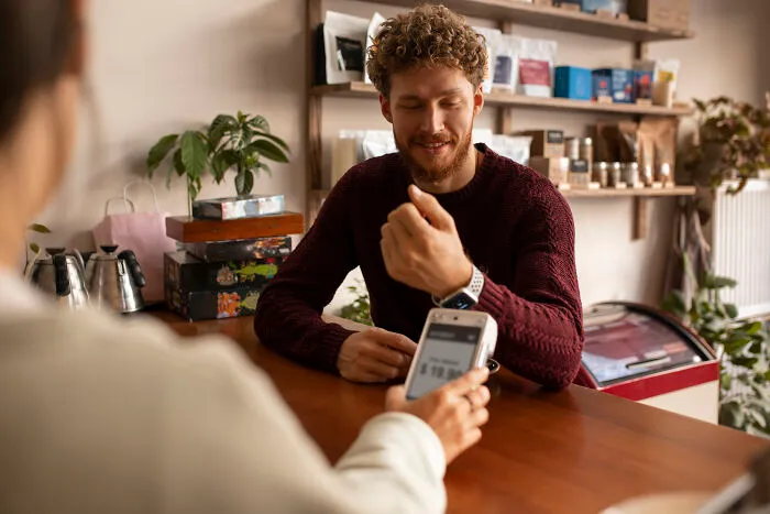 A customer paying with a smart watch, highlighting daily interactions affected by subtle sexism