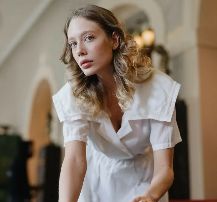 A blonde woman in a white dress looking forward, showcasing the contrast between rich people and having class