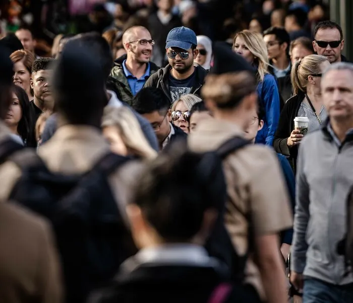 A large crowd of people walking on a city street, representing public reactions to major scandals.