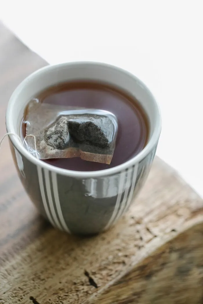 A close-up of a tea bag steeping in a ceramic mug, capturing a simple moment in middle-class life