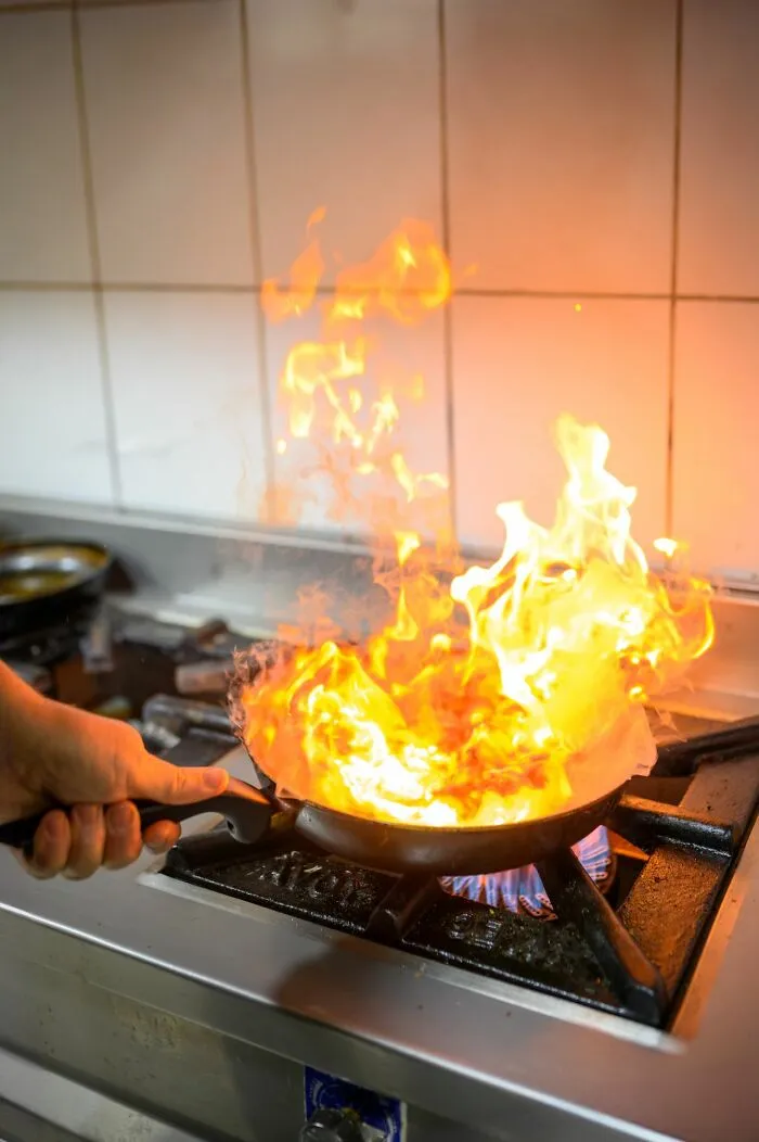 A kitchen pan catching fire on a stove, demonstrating fire safety facts that could make a huge difference in an emergency