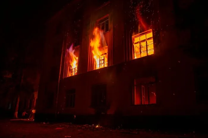 Flames bursting from the windows of a dark building, illustrating a critical emergency.